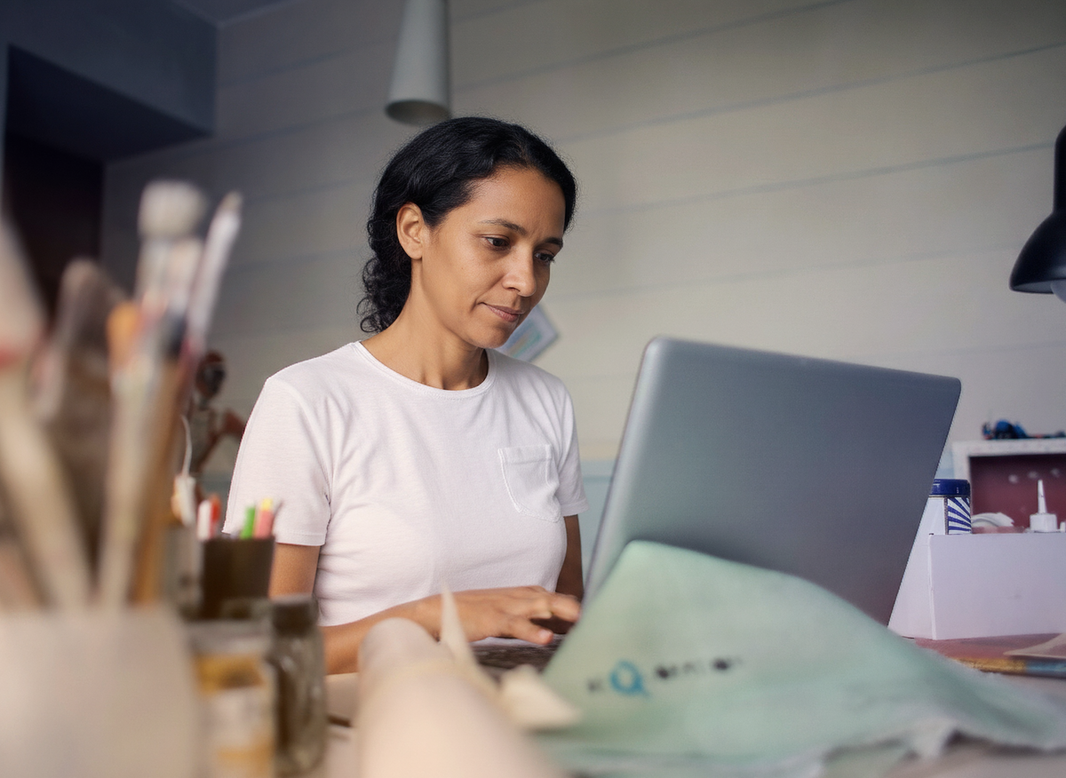 Dona de uma pequena empresa de serviços lendo o relatório do Distilo no notebook, na própria bancada